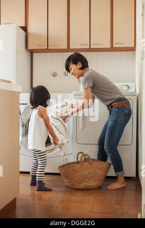 Mother and daughter putting towel into washing machine