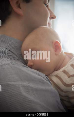 Baby boy sleeping on father's shoulder, close up Stock Photo