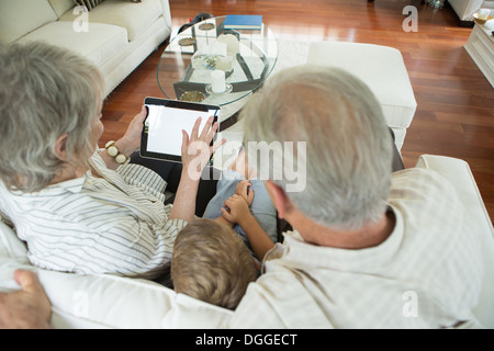 Grandparents showing boy digital tablet on sofa Stock Photo