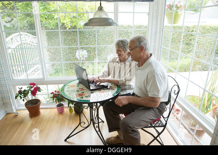 Senior couple using laptop in conservatory Stock Photo