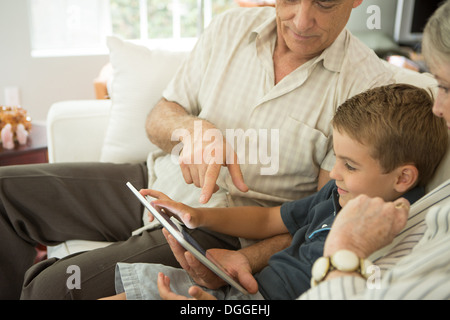 Grandparents sitting with grandson and looking at digital tablet Stock Photo