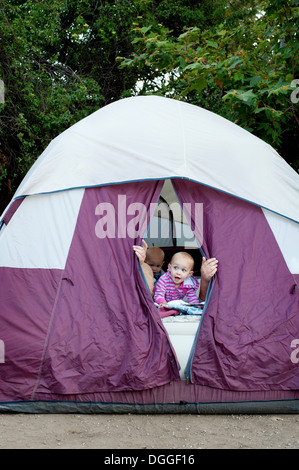 Toddler twins and father peeking out of tent Stock Photo