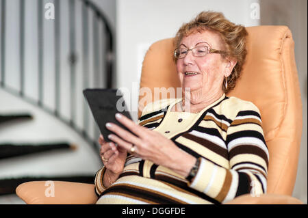 Smiling elderly woman reading an eBook Stock Photo