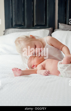 Girl sitting with baby brother on bed