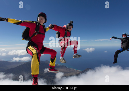 Small group of skydivers reaching to join hands Stock Photo