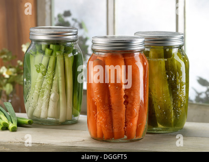 Three jars of pickled vegetables on windowsill Stock Photo