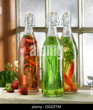 Three bottles of pickled herbs on windowsill Stock Photo