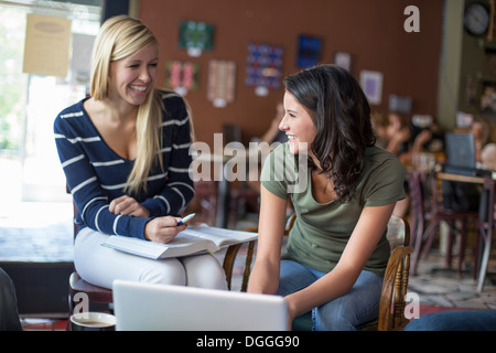 Two teenagers studying with textbooks and computer in cafe Stock Photo