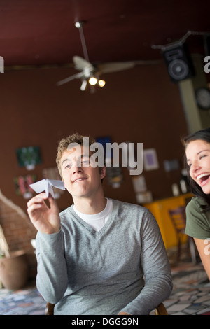 Young man holding paper airplane in coffee house Stock Photo