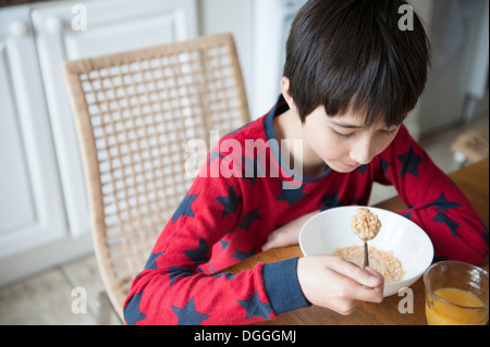 Boy eating breakfast cereal at table Stock Photo