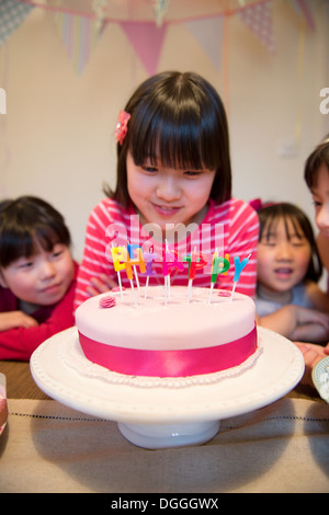 Girl looking at birthday candles on cake Stock Photo