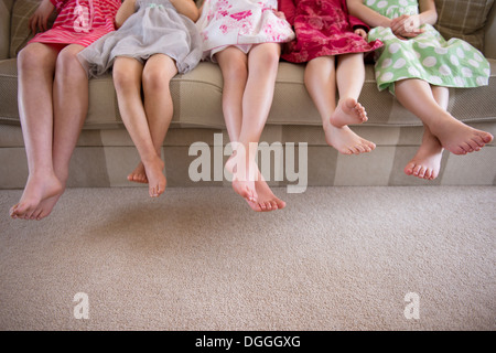Girls sitting together in a row on sofa Stock Photo