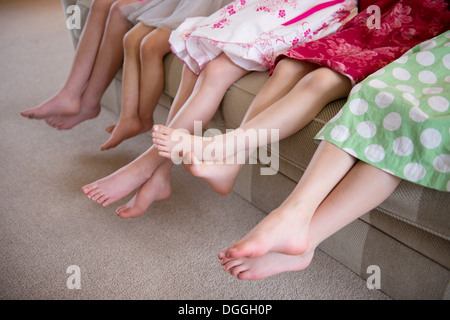 Girls sitting together in a row on sofa Stock Photo