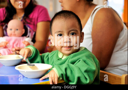 Boy with a lively look eating porridge, mother-child group in Puebla, Mexico, Central America Stock Photo