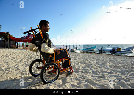 Lobster fisherman suffering from the bends after a diving accident sitting in his wheelchair at the beach, Cancun Stock Photo