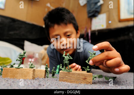 Boy playing with plastic toy soldiers, in a poor district of Cancun, Yucatan Peninsula, Quintana Roo, Mexico, Latin America Stock Photo