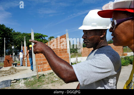 Construction supervisor and the president of the "Esperanca" housing co-operative inspecting the building site, each family Stock Photo