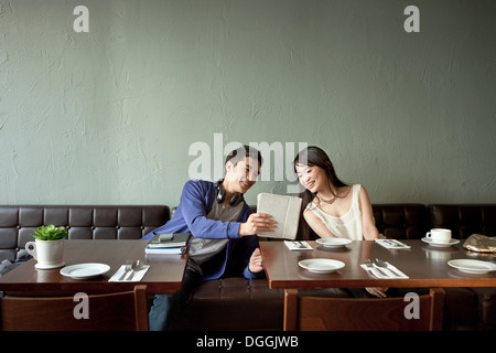 Young man showing young woman digital tablet in restaurant Stock Photo