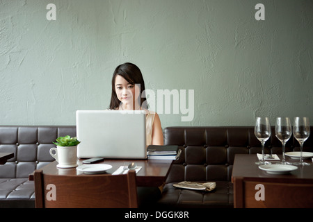Young woman using laptop in restaurant Stock Photo