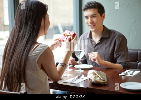 Young couple in restaurant, woman holding gift box Stock Photo