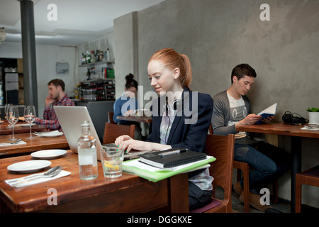 Young woman using laptop in cafe Stock Photo