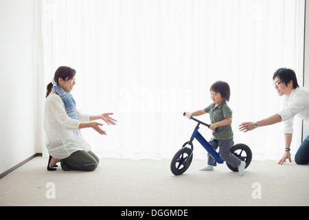 Parents with son learning to ride bicycle Stock Photo