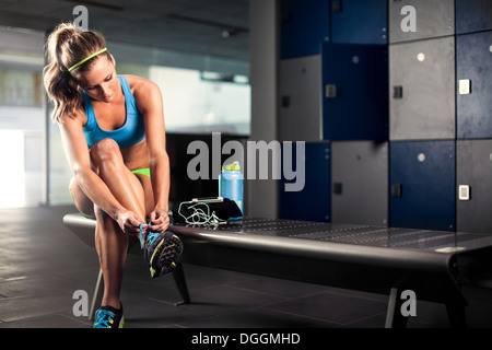 Young woman tying trainer lace in gym Stock Photo