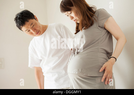 Man and pregnant woman looking down at stomach, portrait Stock Photo