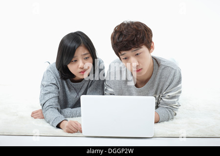 a boy and a girl lying down with a laptop Stock Photo