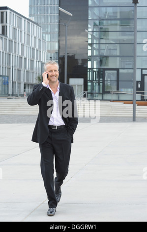 Mature man walking in financial district and using cellphone Stock Photo
