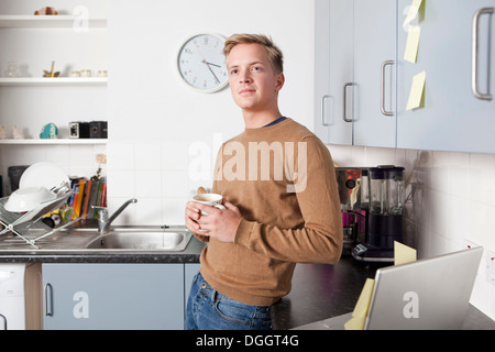 Young man in kitchen with coffee cup Stock Photo