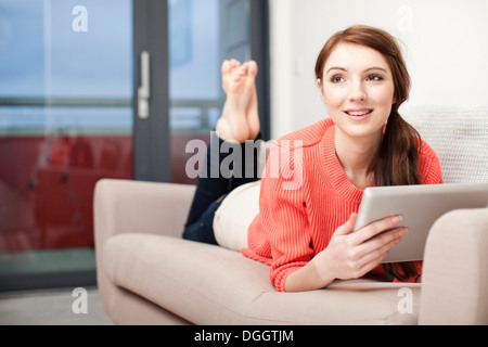 Young woman lying on sofa using digital tablet Stock Photo