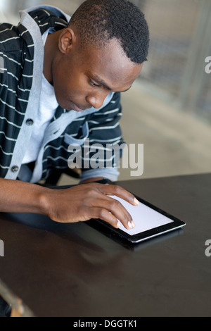 Eighteen year old male sitting at a desk and using an ipad. Stock Photo