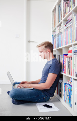 Young man sitting on floor using laptop Stock Photo