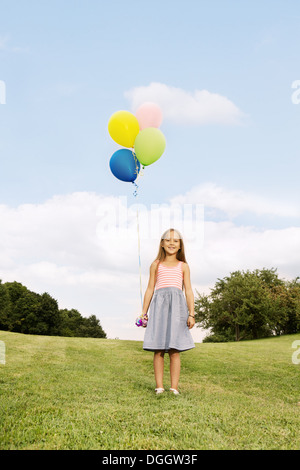 Girl on grass holding balloons Stock Photo - Alamy