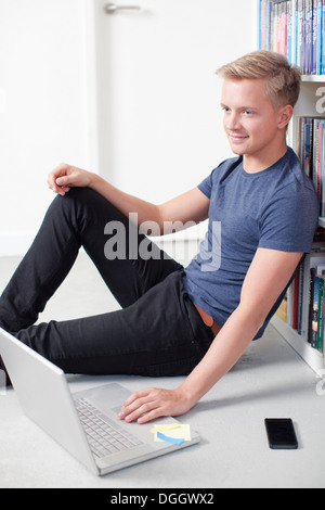 Young man sitting on floor using laptop Stock Photo
