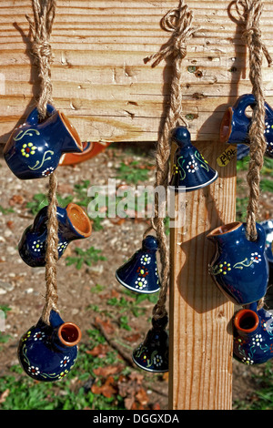 Pitchers and ceramic bells, hanging with strings on a plank of wood. Stock Photo