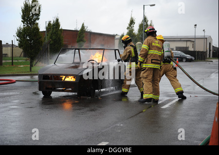 Firefighters from the 100th Civil Engineer Squadron Fire Department extinguish a flaming car before the third annual Fire Muster Oct. 10, 2013, on RAF Mildenhall, England. During the muster, Team Mildenhall members completed several firefighter-themed tas Stock Photo