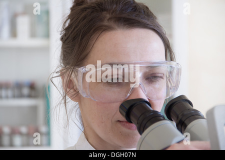 Female scientist looking through microscope Stock Photo