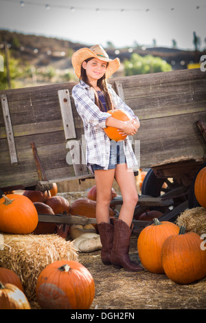 Preteen Girl Wearing Cowboy Hat Portrait at the Pumpkin Patch in a Rustic Setting. Stock Photo