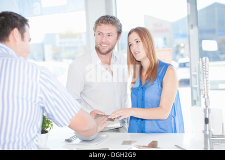 Young couple talking with salesman in kitchen showroom Stock Photo