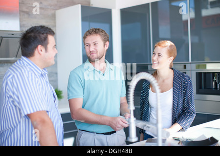 Young couple with salesman in kitchen showroom Stock Photo