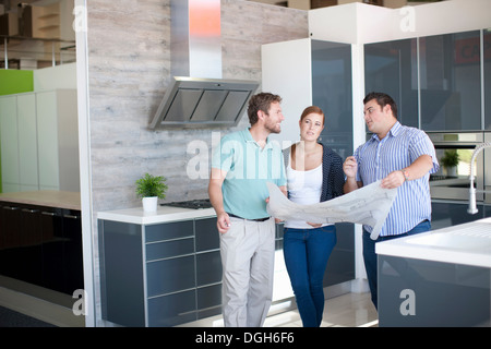 Young couple with salesman in kitchen showroom Stock Photo