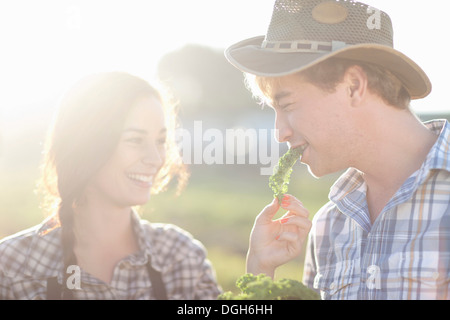Young couple trying vegetables on farm Stock Photo
