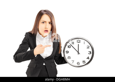 Angry young businesswoman pointing on a wall clock Angry young businesswoman pointing on a wall clock