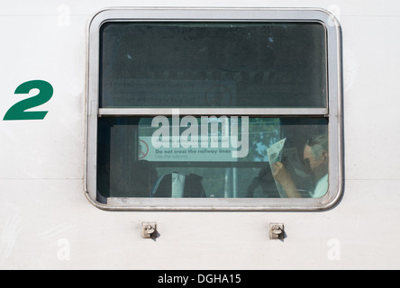Man reading newspaper in the window of a Trenitalia railway carriage, Italy, Europe Stock Photo
