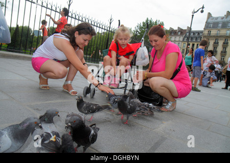 Paris France,Europe,French,4th arrondissement,Île de la Cité,Place Jean-Paul II,adult,adults,woman women female lady,mother mom,feeding,pigeons,girl g Stock Photo