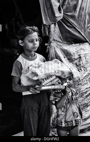 Poor Indian lower caste girl receiving free food and clothes outside her bender / tent.  Andhra Pradesh, India. Monochrome Stock Photo