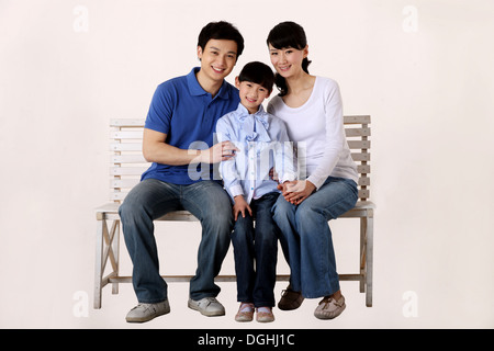 East Asian One Child Family Sitting on the Chair, Smiling, Looking at the Camera Stock Photo