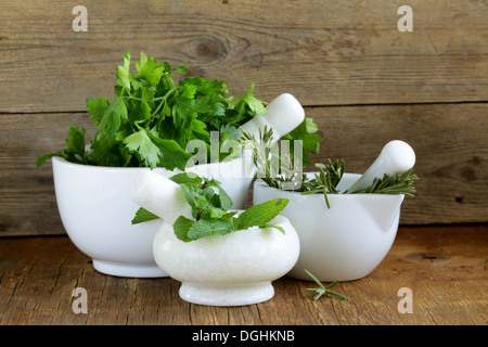 marble mortar with different herbs on a wooden background Stock Photo